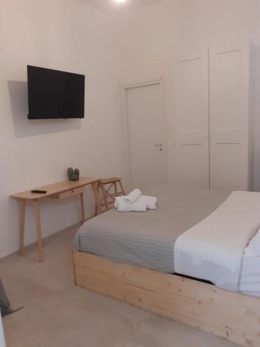 een slaapkamer met een bed, een bureau en een televisie bij arco del sacramento casa vacanze in Benevento