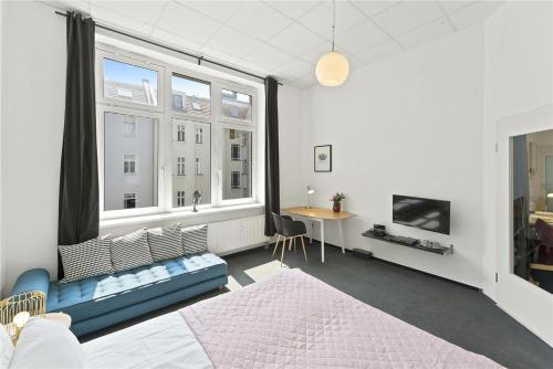 a bedroom with a bed and a desk and windows at Holiday 33 Apartments ABCD Alexanderplatz in Berlin