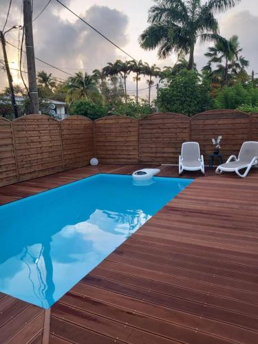 une piscine avec deux chaises et une terrasse en bois dans l'établissement An ti kaz la, à Sainte-Anne