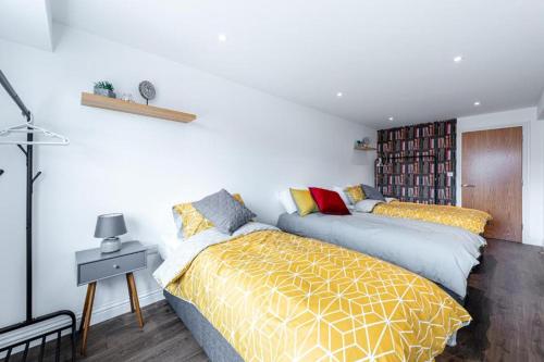 a bedroom with two beds and a book shelf at homely - Watford Central Apartments (Warner Bros Studio) in Watford