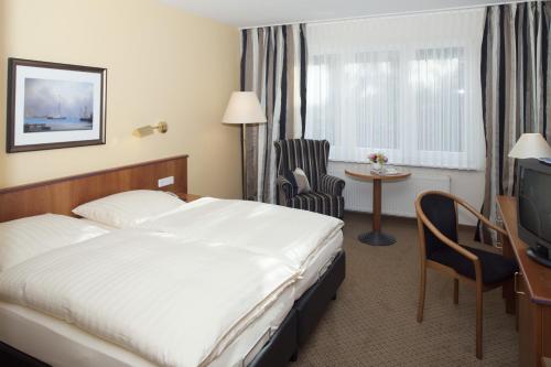 a hotel room with a bed and a desk and a television at Hotel an der Schlei Garni in Fahrdorf