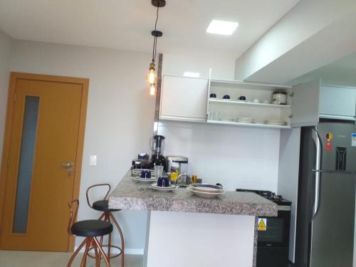 a kitchen with a counter and a refrigerator at Flat Paraiso dos Coqueiros in Guarajuba