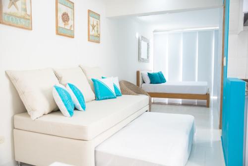 sala de estar con sofá blanco y almohadas azules en Cristal Caribbean Rodadero Santa Marta, en Santa Marta