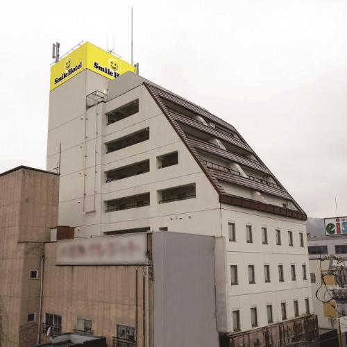 a white building with a yellow sign on top of it at Smile Hotel Nabari in Nabari