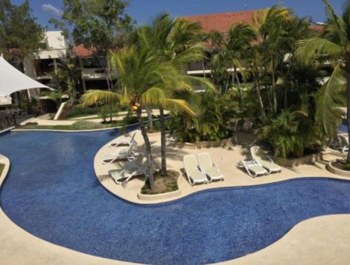 a resort with a pool with lounge chairs and palm trees at Private family room in Coronado Luxury Club & Suites in Playa Coronado