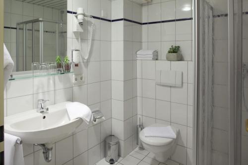 a white bathroom with a sink and a toilet at Hotel an der Schlei Garni in Fahrdorf