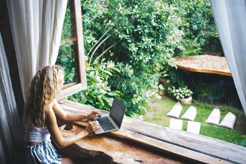 a woman sitting in a window with a laptop at Roots Tree House in Uluwatu