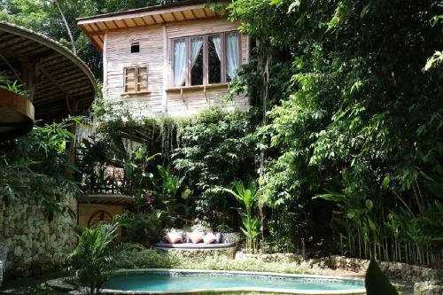 a house with a garden with a swimming pool at Roots Tree House in Ungasan
