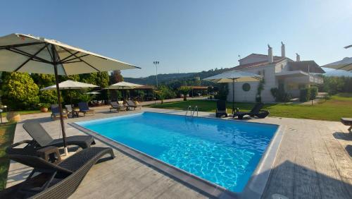 una piscina con sillas y sombrillas junto a una casa en Ktima Xiliadou, en Chiliadou