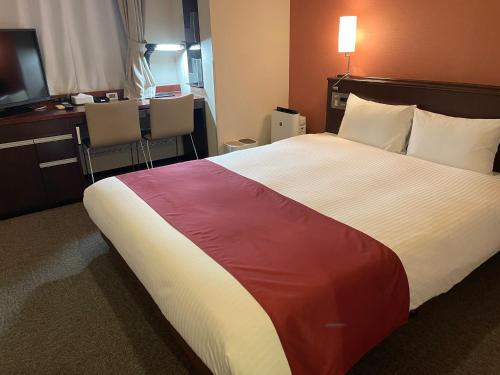 Ai Hotel Keikyu Kamata-ekimae في طوكيو: غرفة في الفندق مع سرير كبير مع بطانية ملونة