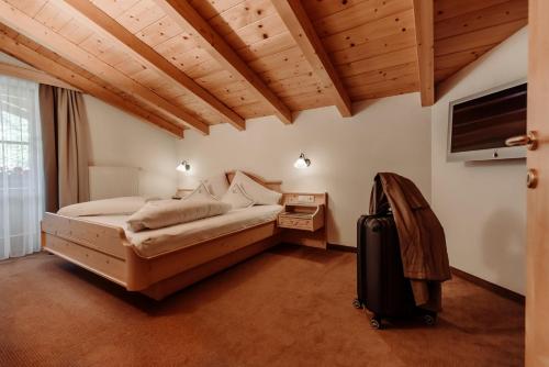 a bedroom with a bed and a television and a suitcase at Ferienwohnungen Renberg in Maria Alm am Steinernen Meer