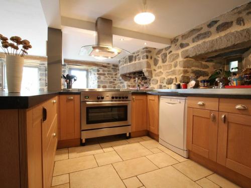 a kitchen with wooden cabinets and a stone wall at Gîte familial restauré avec jardin clos, équipements bébé, animaux acceptés, proche St-Julien-Chapteuil - FR-1-582-296 in Saint-Julien-Chapteuil