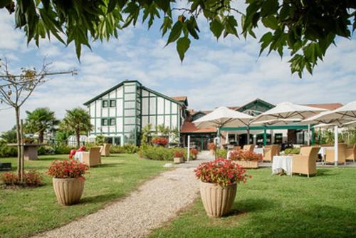 a resort with tables and chairs and a building at Hotel Donibane Saint-Jean-de-Luz in Saint-Jean-de-Luz