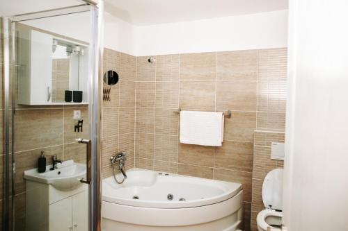 a bathroom with a tub and a toilet and a sink at Kali Host Home Away From Home in Târgu-Mureş