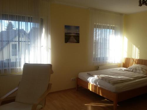 a bedroom with a bed and a chair and windows at Bauernhof Sesterhenn in Leichlingen