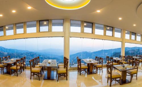 a restaurant with tables and chairs and a large window at Himalaya Drishya Resort in Dhulikhel