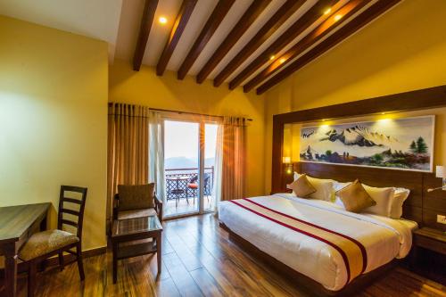a bedroom with a bed and a desk and a window at Himalaya Drishya Resort in Dhulikhel