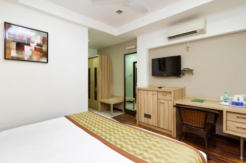 a hotel room with a bed and a desk and a tv at Hotel City Centre Residency in Bangalore