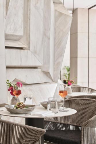 a table with two chairs and two glasses of wine at Athens Capital Center Hotel - MGallery Collection in Athens