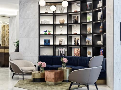 a lobby with a blue couch and two chairs at Athens Capital Center Hotel - MGallery Collection in Athens