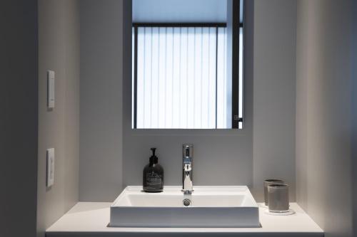 a bathroom sink with a bottle of alcohol on it at MIROKU NARA by THE SHARE HOTELS in Nara