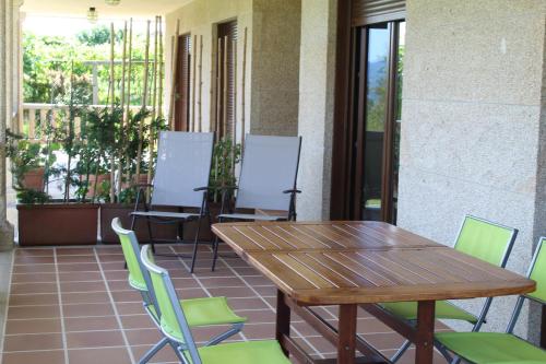 einen Holztisch und Stühle auf einer Terrasse in der Unterkunft CASA DE AREAS in Sanxenxo