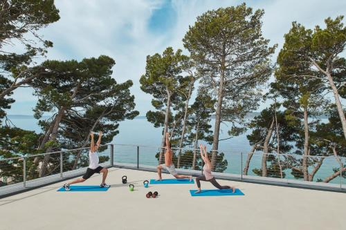 a group of three people doing a yoga pose on a roof at Bluesun hotel Berulia in Brela