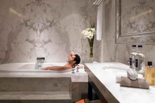 a woman laying in a bath tub in a bathroom at Leofoo Residences in Taipei