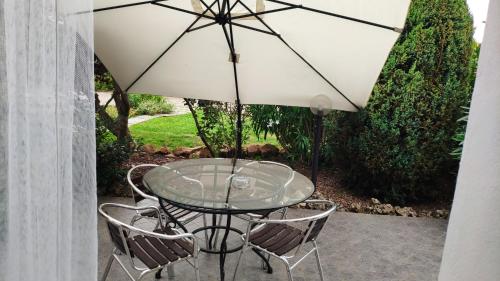 a glass table with two chairs and an umbrella at B&B La Casetta in Gattinara