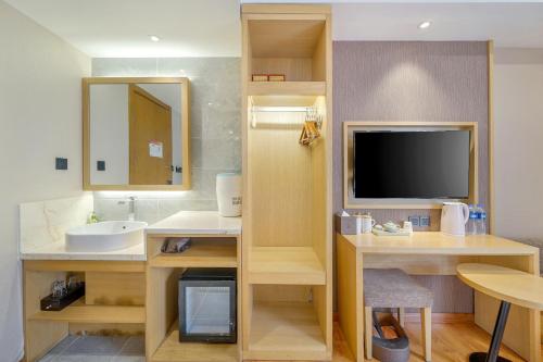 a bathroom with a sink and a tv in a room at Harbin Joy Boutique Hotel in Harbin