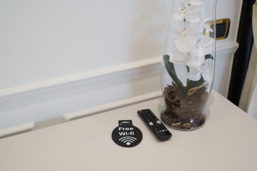 a vase with white flowers and a remote control on a table at Caffetteria Luca Suite & Rooms in Bronte