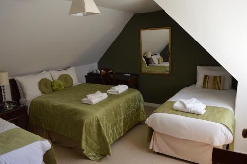 1 dormitorio con 2 camas y espejo en Bennachie Lodge Hotel in Kemnay en Inverurie