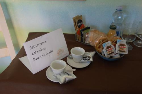 a table topped with two cups and a bowl of food at Hotel Sa Cralla Villasimius in Villasimius