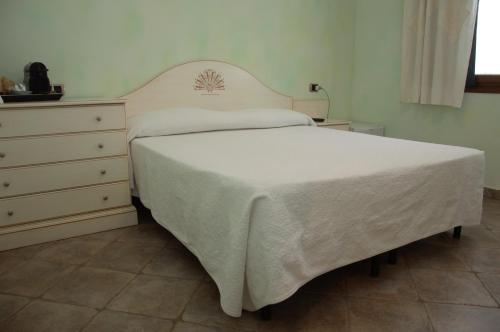 a bedroom with a white bed and a dresser at Hotel Sa Cralla Villasimius in Villasimius