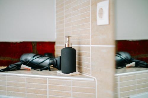 a black soap dispenser on a counter in a bathroom at Kali Host Home Away From Home in Târgu-Mureş