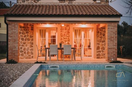 Una casa con una mesa y sillas al lado de una piscina. en Villa Pepina, en Risika
