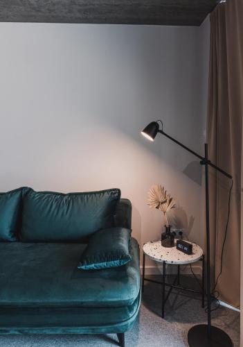 a living room with a green couch and a lamp at Dobosi Birtokközpont in Szentantalfa