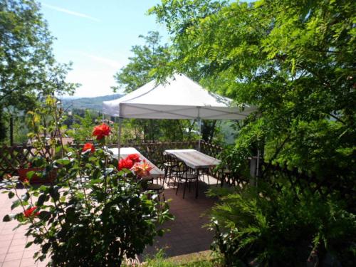 a patio with a white umbrella and tables and chairs at Agriturismo La Quiete in Roncofreddo