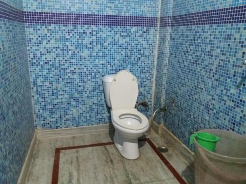 - une salle de bains pourvue de toilettes dans une chambre dotée de carrelage bleu dans l'établissement Hotel Roma Villa, à New Delhi