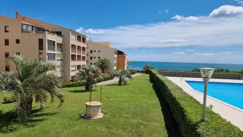 un complexe avec une pelouse et une piscine dans l'établissement Appartement magnifique vue Mer tout confort, au Cap d'Agde