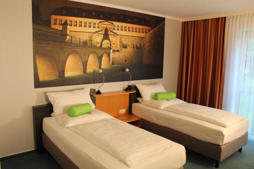 a room with two beds and a painting on the wall at H+ Hotel Erfurt in Erfurt