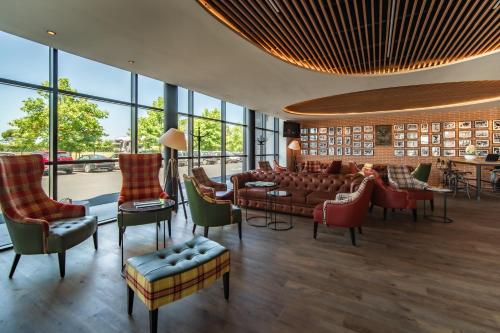 a lobby with a couch and chairs and windows at ibis Styles Castelnaudary in Castelnaudary
