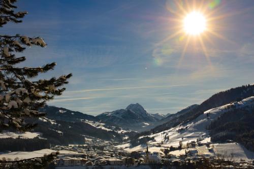 a snow covered mountain with the sun in the sky at Hotel Garni Wieshof in Kirchberg in Tirol