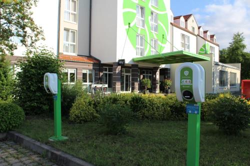 two parking meters in the grass in front of a building at H+ Hotel Erfurt in Erfurt