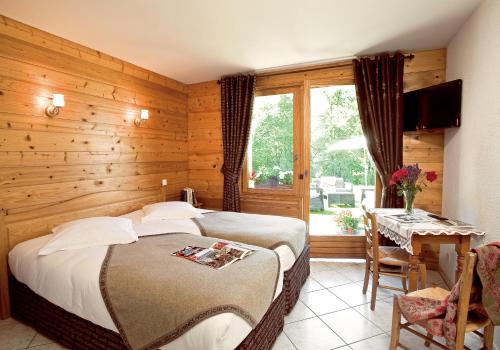 a bedroom with two beds and a table and a window at La Passerelle chambre au calme proche la Clusaz et Grand Bornand in Saint-Jean-de-Sixt