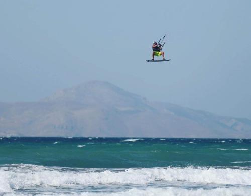 a person flying in the air over the ocean at Royal Bay Suites in Kefalos