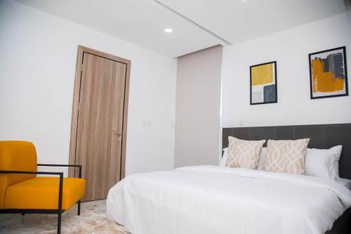 a bedroom with a bed and a yellow chair at MiVi - Midtown Victoria Island in Lagos