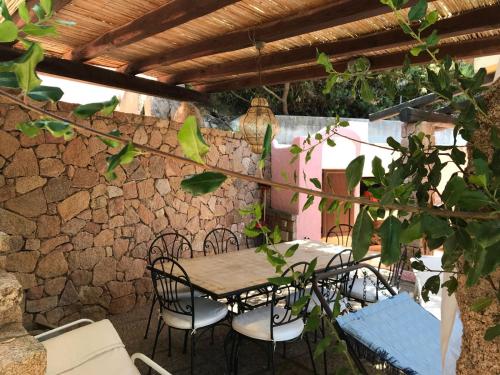 a table and chairs on a patio with a stone wall at Villetta Meravigliosa in Rena Majore