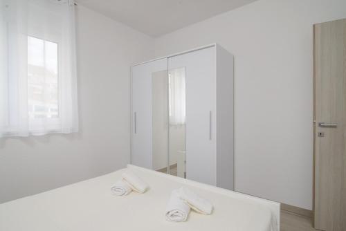 biała łazienka z umywalką i lustrem w obiekcie Apartmani Manuela w Okrugu Gornjim