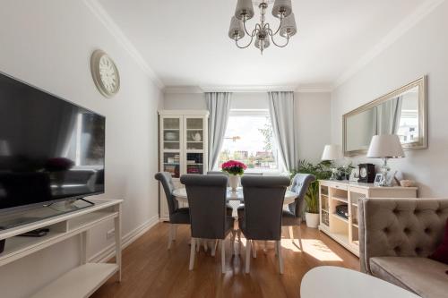 a living room with a table and chairs and a television at Elegant near Old Town - free parking in Gdańsk